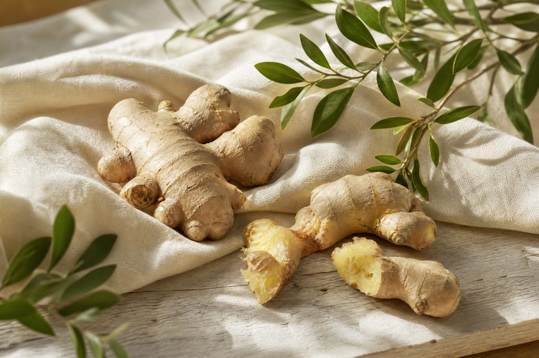 Fresh ginger root on linen with green leaves