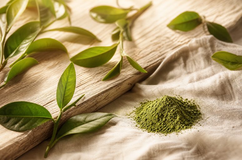 Green tea leaves and matcha powder on a wooden board